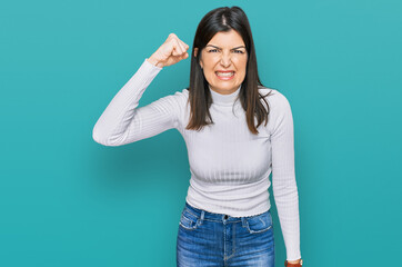 Beautiful brunette woman wearing casual clothes angry and mad raising fist frustrated and furious while shouting with anger. rage and aggressive concept.