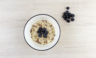 Oatmeal in a round white plate with blueberries. Healthy breakfast food