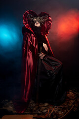 Fabulous creature, historical character, fantasy queen, witch, in costume. Woman, model after 60, in the studio, dark background