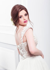 Beautiful bride in wedding dress in luxurious apartment. Fashion makeup and hairstyle. Portrait of young gorgeous bride. Wedding. Studio shot.