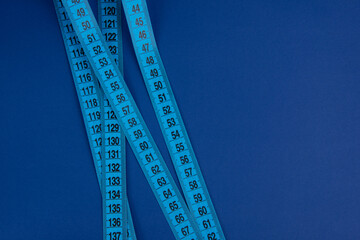 Blue tape measure on the bright blue background