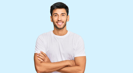Young handsome man wearing casual white tshirt happy face smiling with crossed arms looking at the...