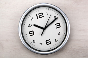 large white clock face with digits on a wooden background closeup