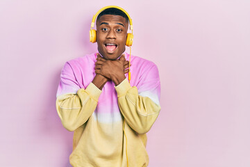 Young black man listening to music wearing headphones shouting and suffocate because painful strangle. health problem. asphyxiate and suicide concept.