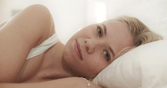 Pretty Woman Lying on Her Side While in Bed as She Stares into the Camera