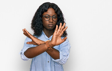 Beautiful african young woman wearing casual clothes and glasses rejection expression crossing arms doing negative sign, angry face