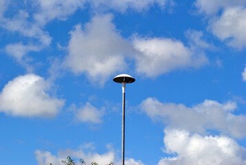 Single Modern Street Lamp Isolated against Blue Sky with White Clouds 
