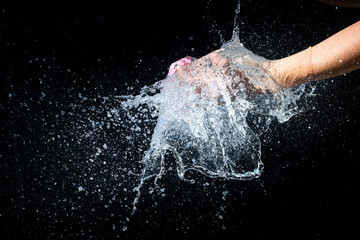 Water balloon bursting in hands