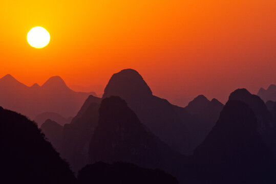 Sun rises over landscape of myriad silhouetted karst towers, Yangshuo, Guilin, China   