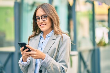 Young hispanic businesswoman smiling happy using smartphone at the city.