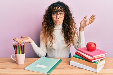Young hispanic girl studying for school exam clueless and confused with open arms, no idea and...
