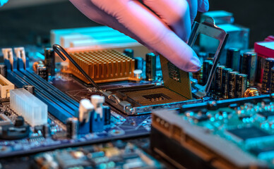 Engineer's gloved hand is holding the CPU chip on the background of the motherboard. High-tech hardware microelectronics - obrazy, fototapety, plakaty