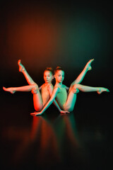 Touch. Two young gymnasts together in neon colored lights on a black background. The concept of gymnastics and modern choreography. Creative art photo.