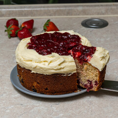 cherry cake with cream cheese and cherries on cream, on a stone table top on a background of strawberries.