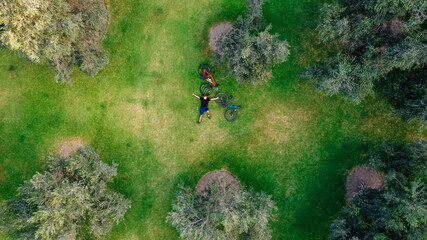 Aerial drone view of a cyclist lying down and resting in a meadow