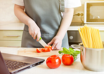 female hands preparing ingredients for pasta on a wooden board. cooking spaghetti with tomatoes and spinach