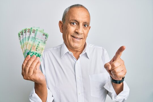 Handsome senior man holding 50 hong kong dollars banknotes smiling happy pointing with hand and finger to the side