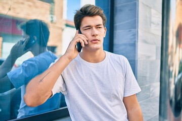 Young caucasian man with serious expression talking on the smartphone at the city.