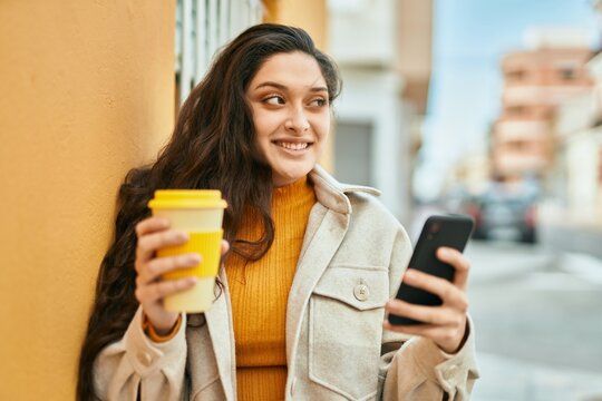 Young middle east woman using smartphone drinking coffee at the city.