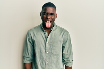 Young african american man wearing casual clothes sticking tongue out happy with funny expression. emotion concept.