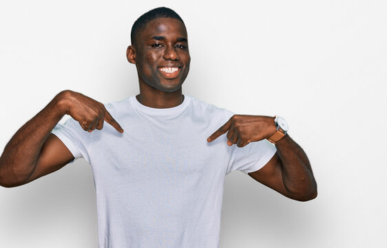 Young african american man wearing casual white t shirt looking confident with smile on face, pointing oneself with fingers proud and happy.