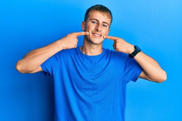 Naklejka premium Young caucasian man wearing casual blue t shirt smiling cheerful showing and pointing with fingers teeth and mouth. dental health concept.