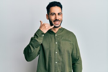 Fototapeta premium Young hispanic man wearing casual clothes smiling doing phone gesture with hand and fingers like talking on the telephone. communicating concepts.