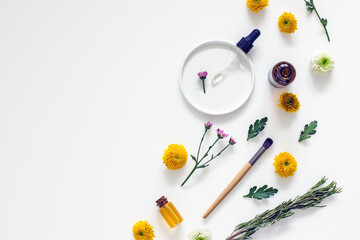 Flat lay cosmetic composition, oil bottles, wellness cosmetics, herbal ingredients, flowers on a white background, top view