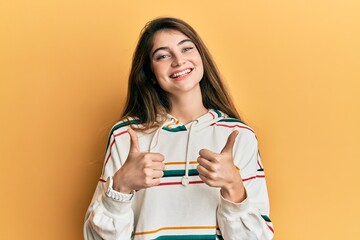 Young caucasian woman wearing casual clothes success sign doing positive gesture with hand, thumbs up smiling and happy. cheerful expression and winner gesture.