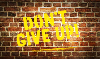 Don't give up sign spray painted on the brick wall