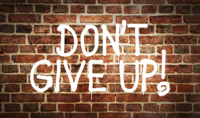 Don't give up sign spray painted on the brick wall