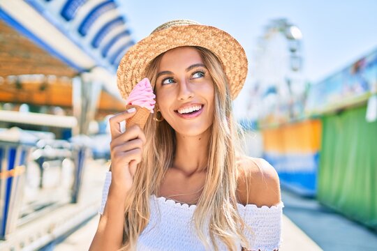 Young blonde tourist girl smiling happy eating ice cream at the fairground.