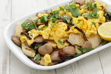 bagila bil dihin, iraqi breakfast; boiled dried broad beans and scrambled eggs over pieces of...