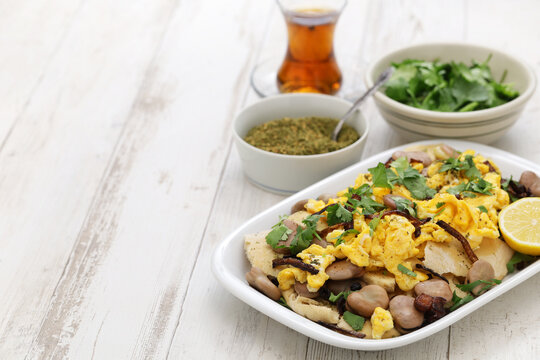 bagila bil dihin, iraqi breakfast; boiled dried broad beans and scrambled eggs over pieces of flatbread
