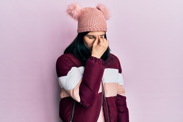 Young hispanic woman wearing wool winter sweater and cap tired rubbing nose and eyes feeling...