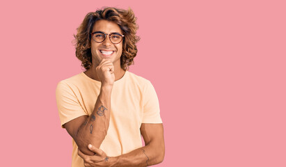 Young hispanic man wearing casual clothes and glasses looking confident at the camera with smile...
