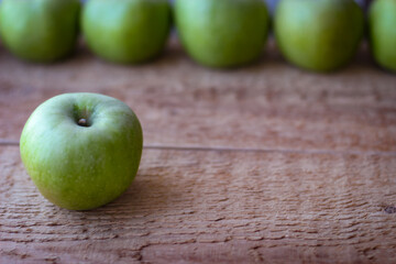Green apples stand on a wooden surface