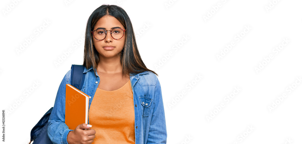 Sticker Young latin girl wearing student backpack and holding books relaxed with serious expression on face. simple and natural looking at the camera.