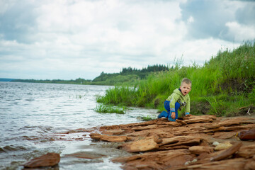Naklejka premium kid playing in the sand and with cameos on the riverbank, selective focus