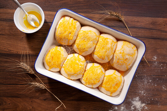 Fresh buns with yolk in a ceramic oven tray ready to bake.