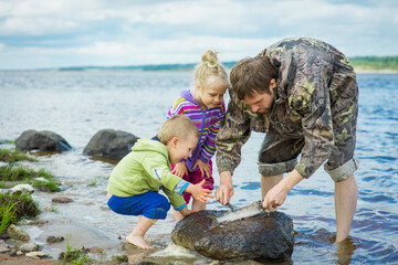 a fisherman with children and a pike on the river bank, selective focus