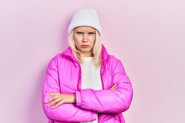 Beautiful caucasian blonde woman wearing wool hat and winter coat skeptic and nervous, disapproving...