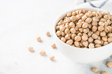 Chickpeas in white bowl at light kitchen table.