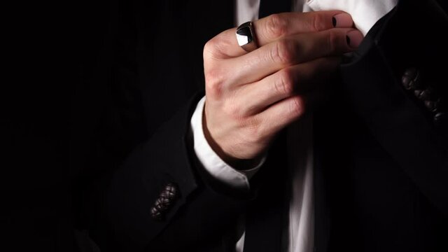 Macro view of a man who is fastening a button on the sleeve of his costume. Closeup footage of a male person who is wearing a suit. A groom is preparing for the wedding. Concept of the formal clothes.