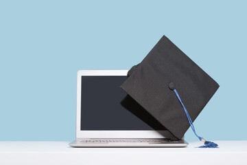 Black Graduation Cap with on laptop. Masters or Bachelors Degree thesis writing. Knowledge online...