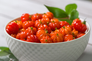 Surinam cherry in a white bowl on a wooden table.