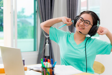 Portrait Asian young woman student glasses headphones stretch oneself from study online class college learning internet education smile looking up teenage girl work distance on laptop computer at home