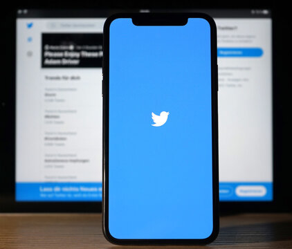 Smartphone zeigt Twitter Logo und steht vor einem Bildschirm welcher die Twitter-Suche mit den aktuellen Trends zeigt, Soziale Netzwerke, 2021