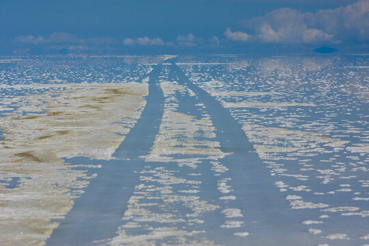 Vehicle tracks leave their mark  in the softened salt bed of the Salar de Uyuni in the rainy season in the Department of Potosi in Bolivia.  