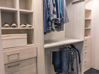 walk in closet with shirts and pants hanging up on hangers and shoes on the shelving